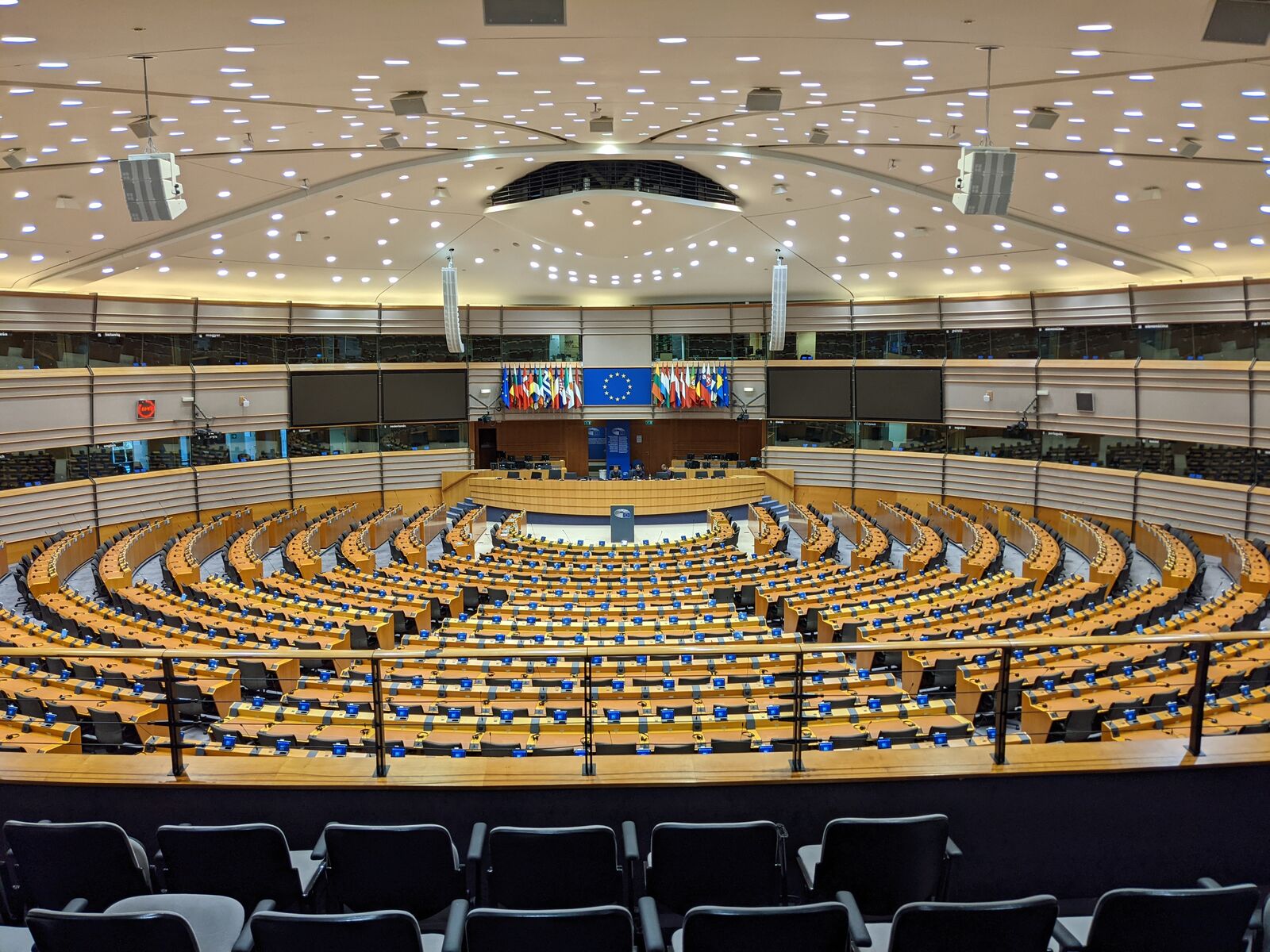 The empty hemicycle of the European Parliament in Brussels, tiers of desks curving around a central podium